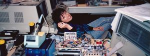 Carol Hatzinger sitting behind her desk filled with electrical components